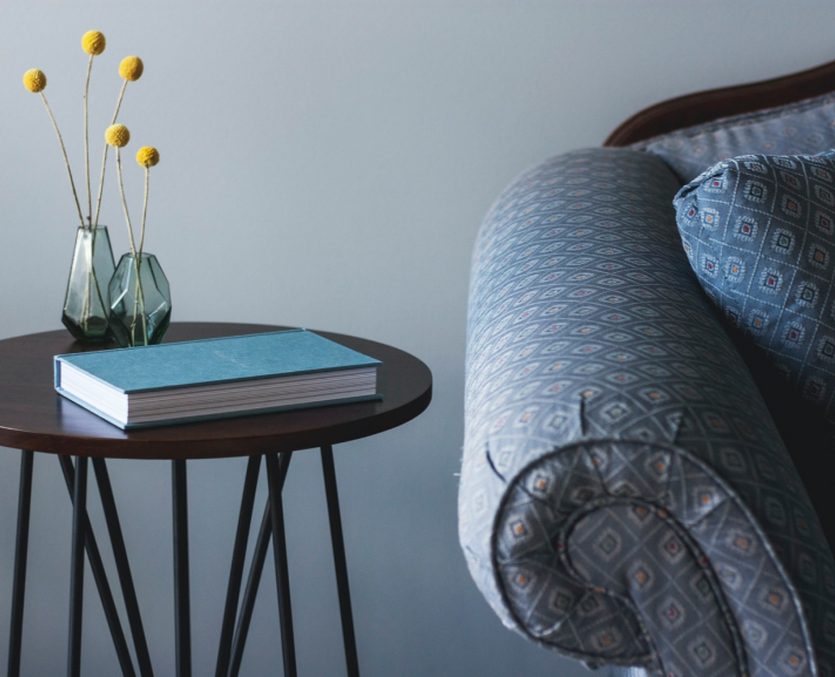 Side table with a book beside an armchair
